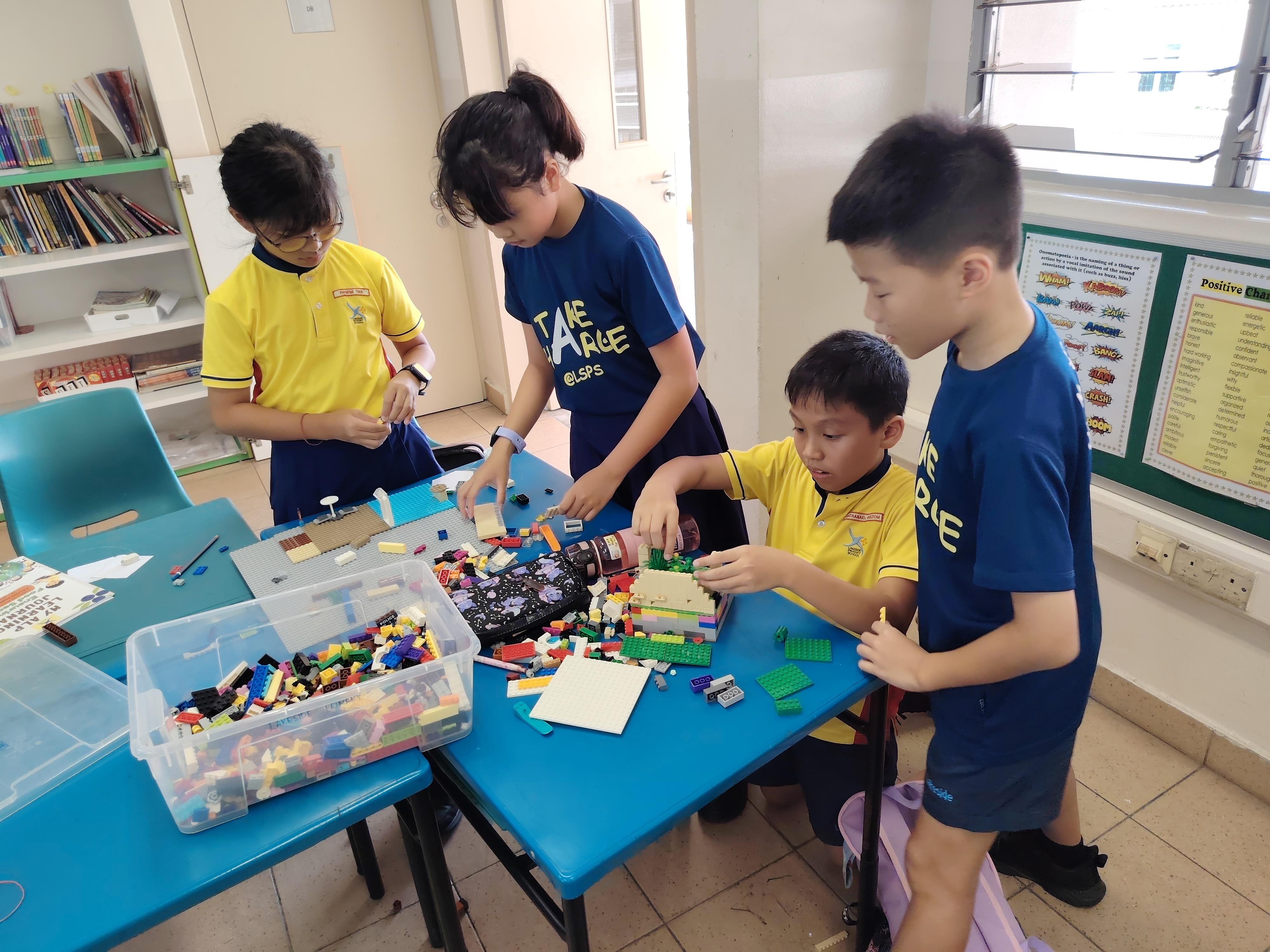 A group of four students working together on their prototype with the provide lego box